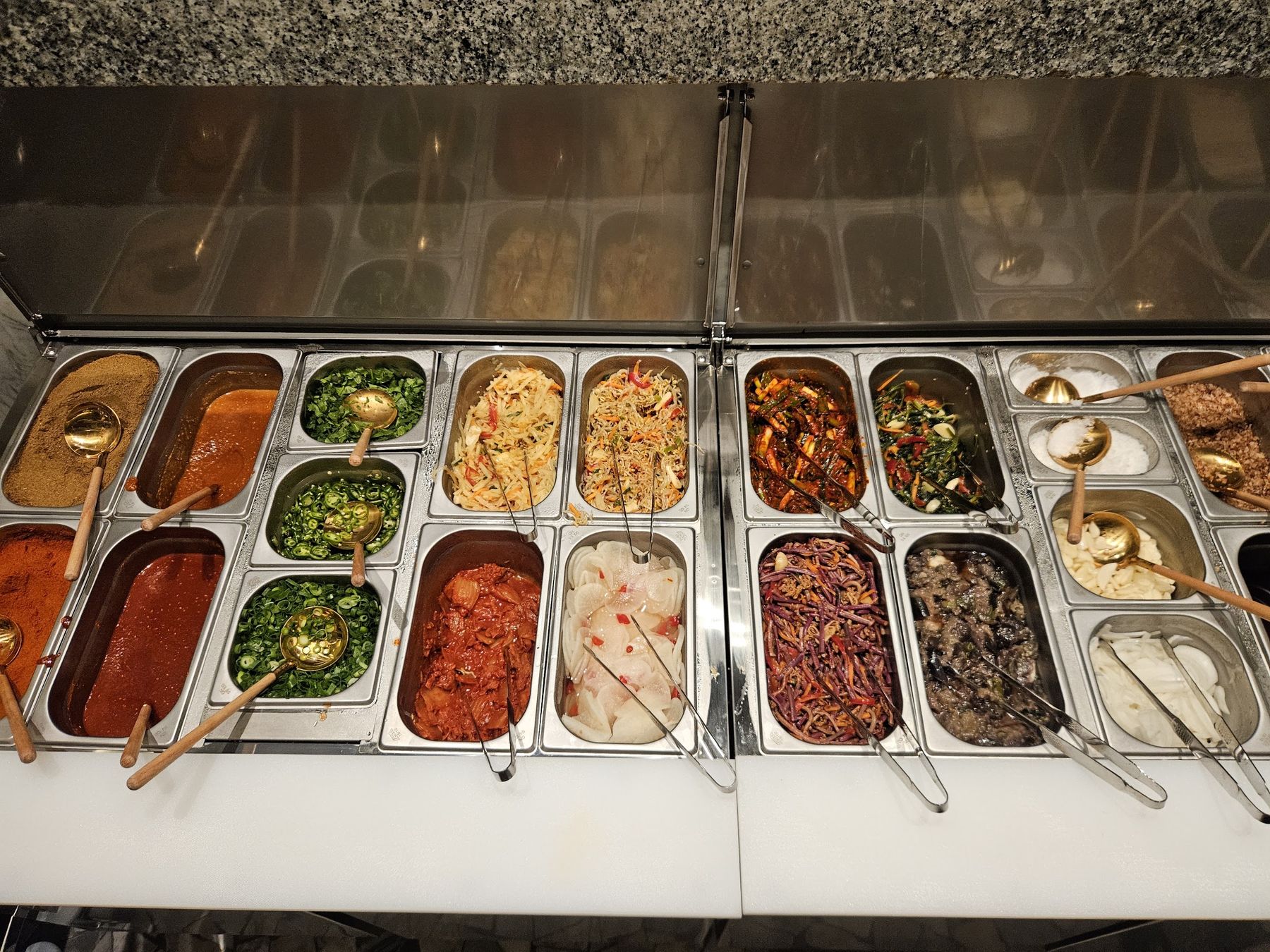 La stazione dei contorni: vaschette di kimchi, verdure, salse