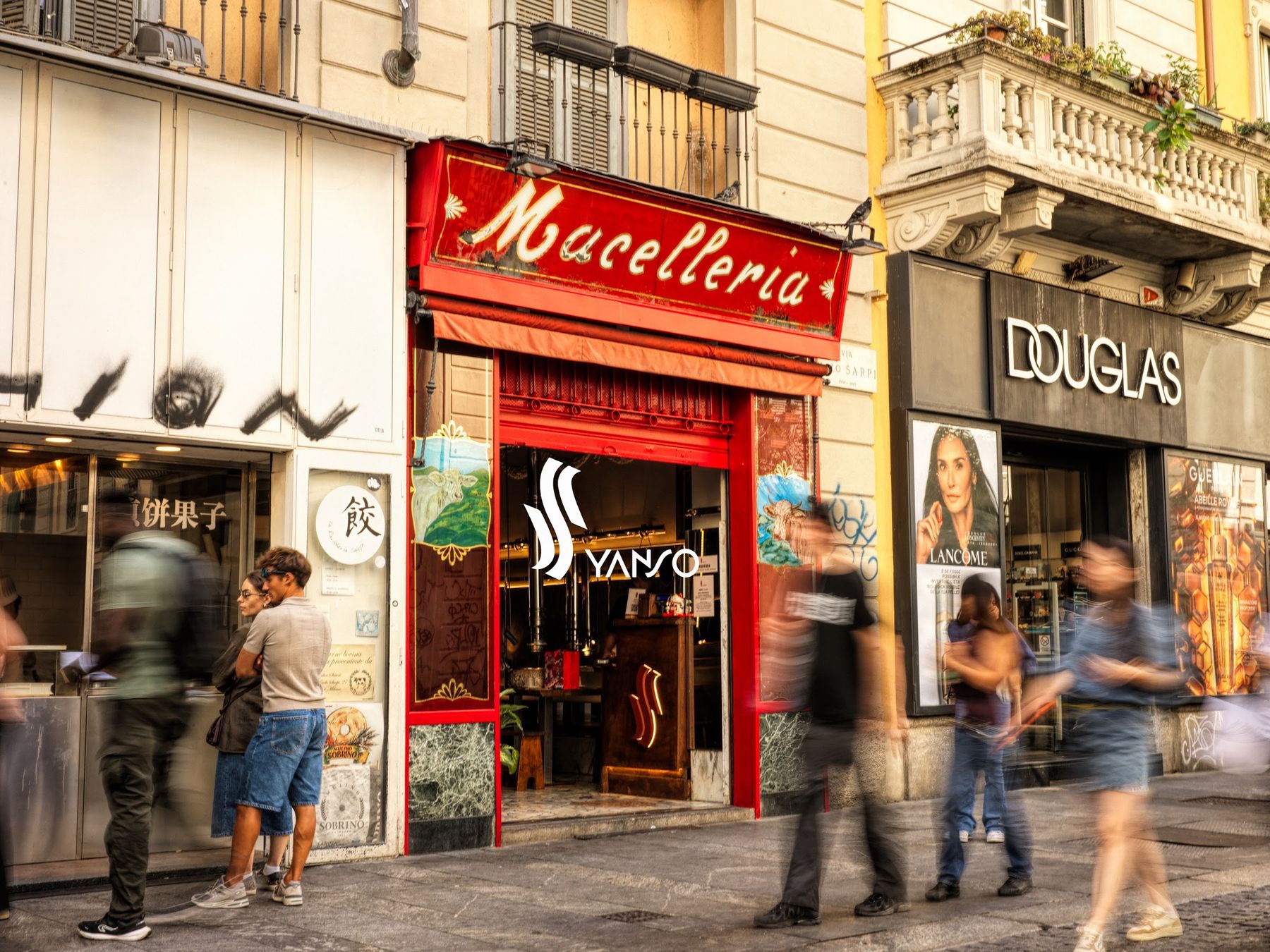 L'ingresso in via Paolo Sarpi: l'insegna rossa Macelleria e la porta con il marchio Yanso, gente che passa