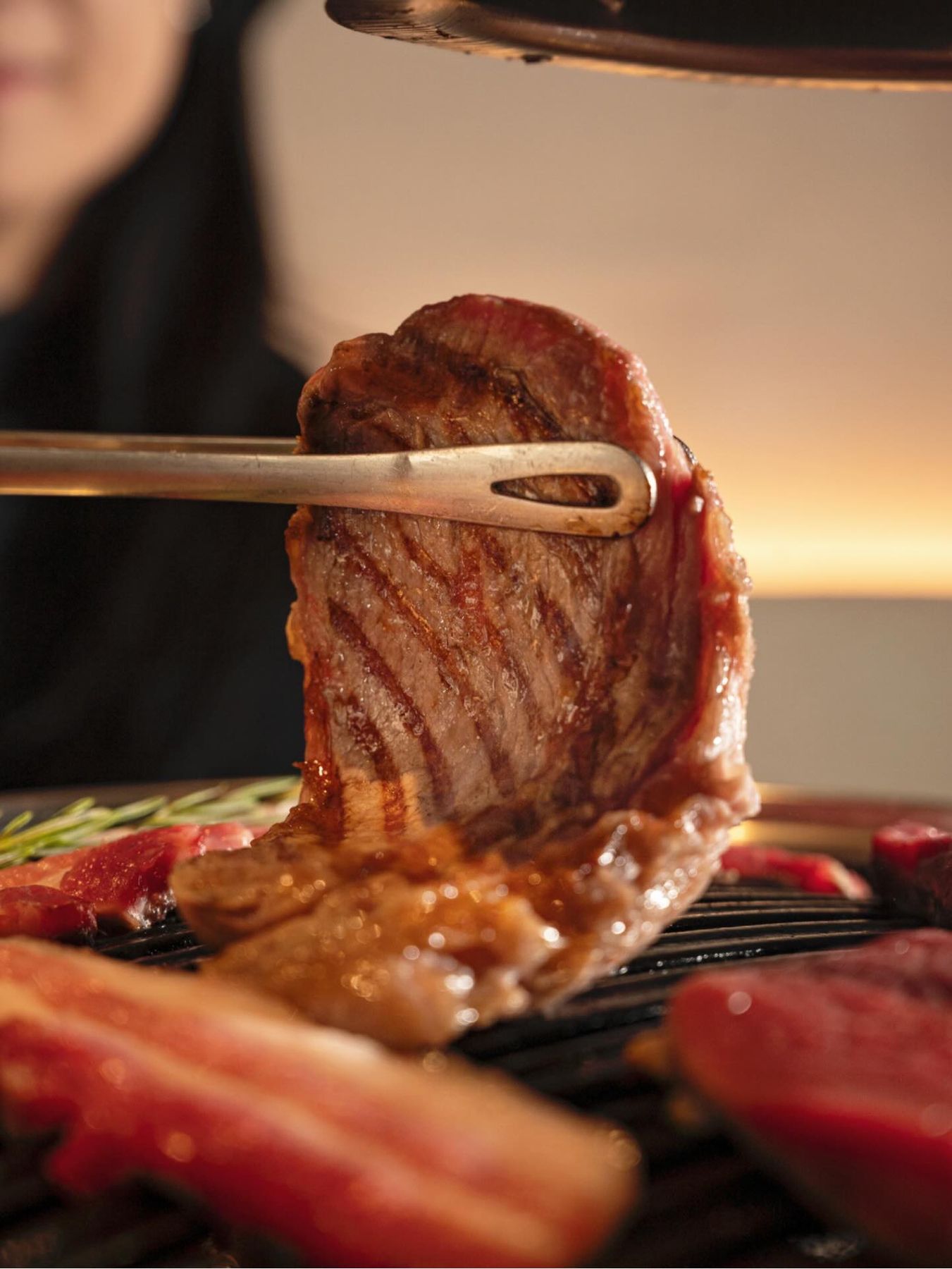 Una bistecca spessa tenuta con le pinze sopra la griglia