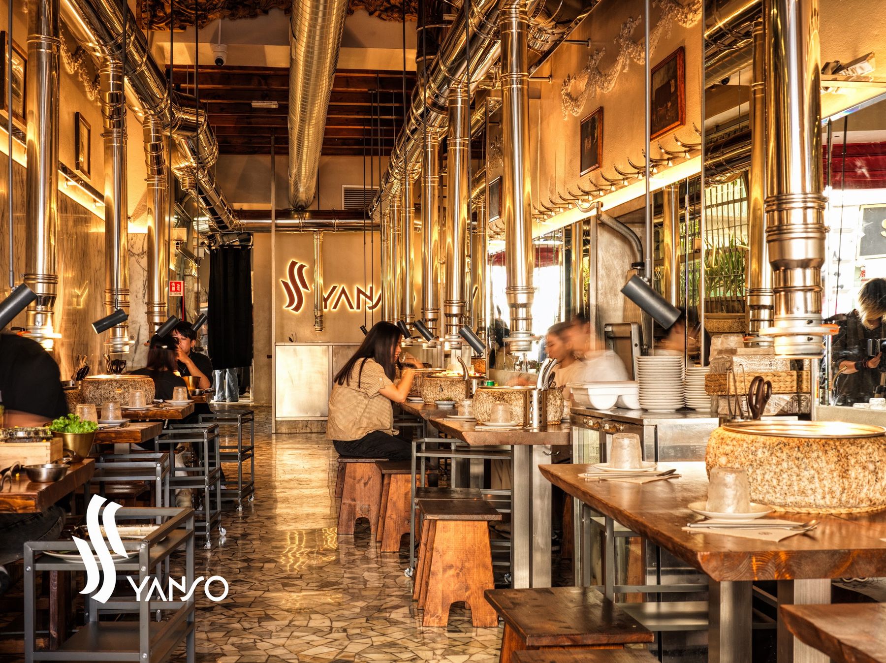 La sala vista dall'ingresso: specchi, luci calde, clienti ai tavoli con i grill