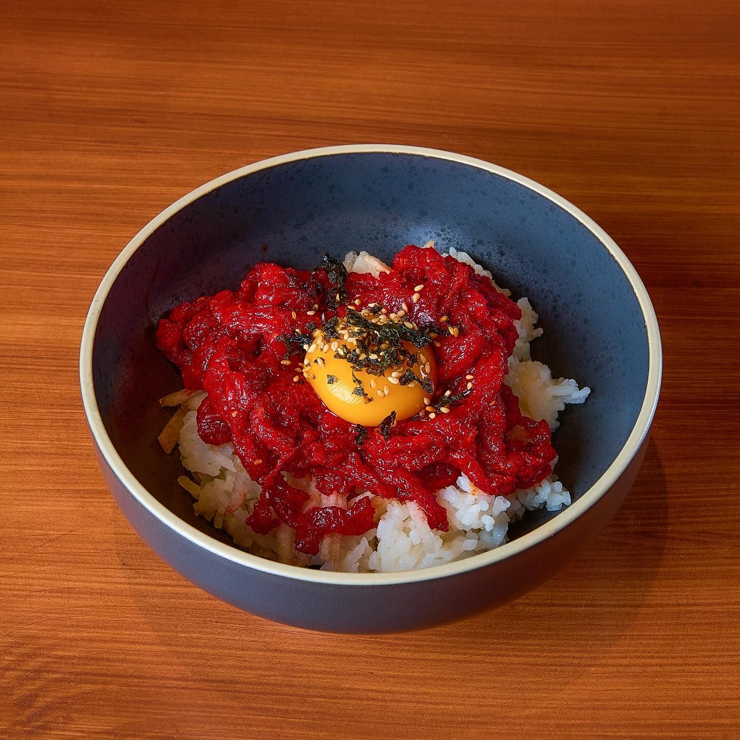 Bibimbap con tartare di manzo e tuorlo crudo in ciotola nera